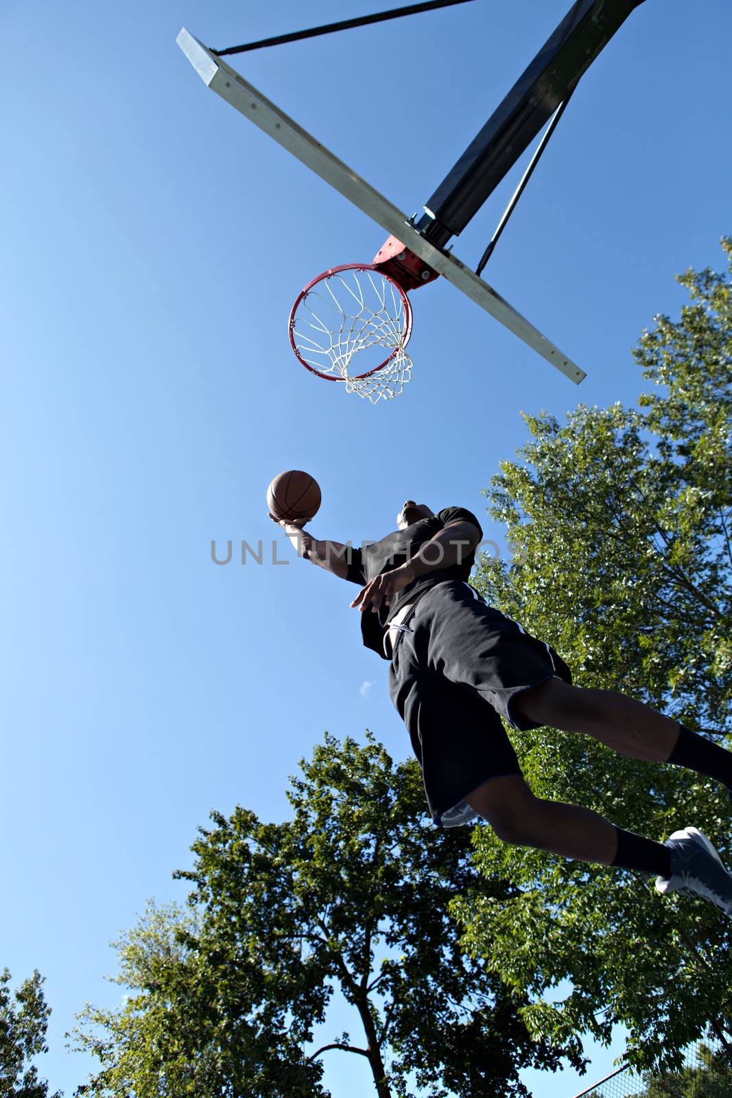 Young basketball player driving to the hoop for a high flying slam dunk.