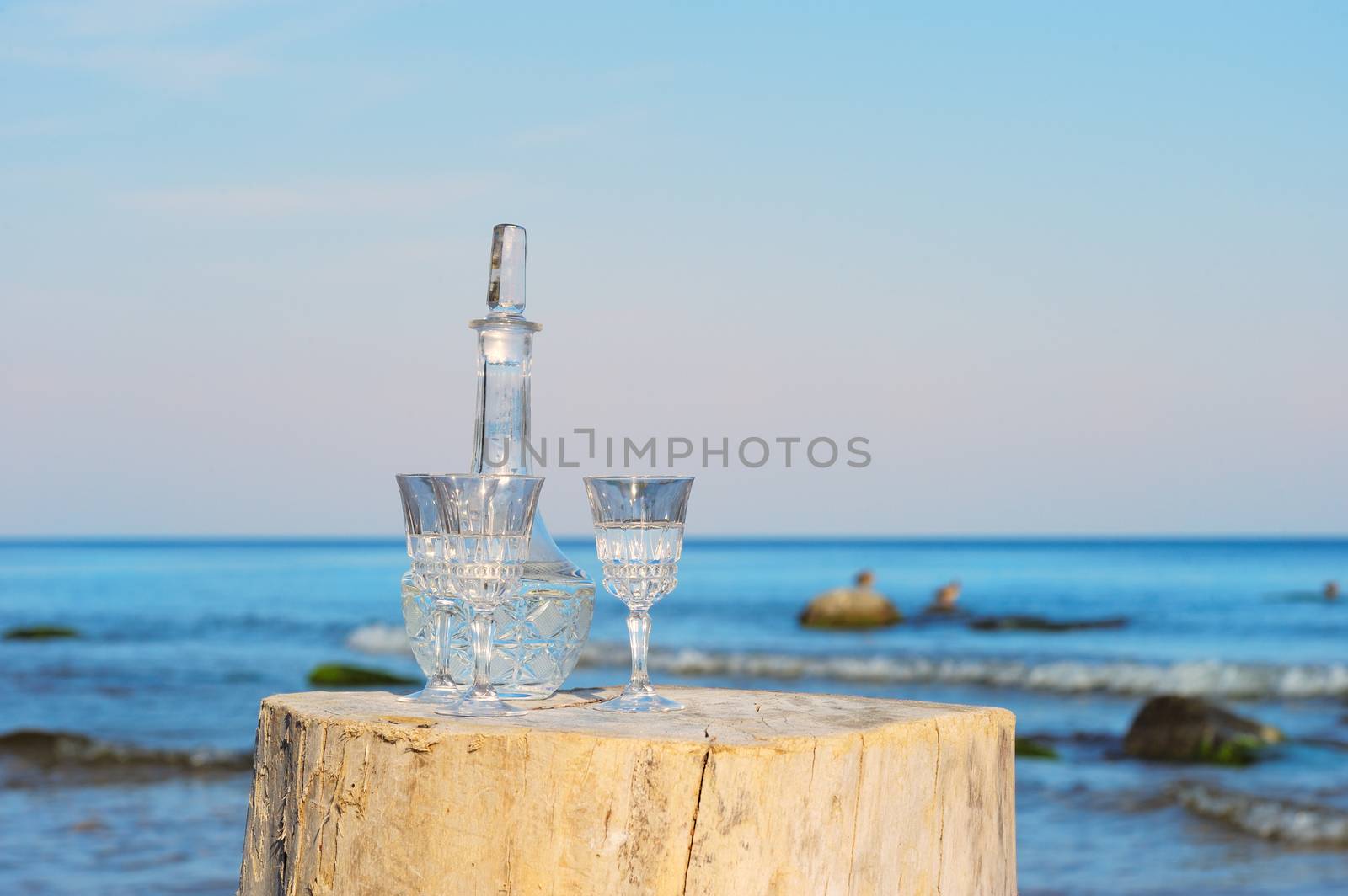 Crystal glasses and decanter on the stump at the sea