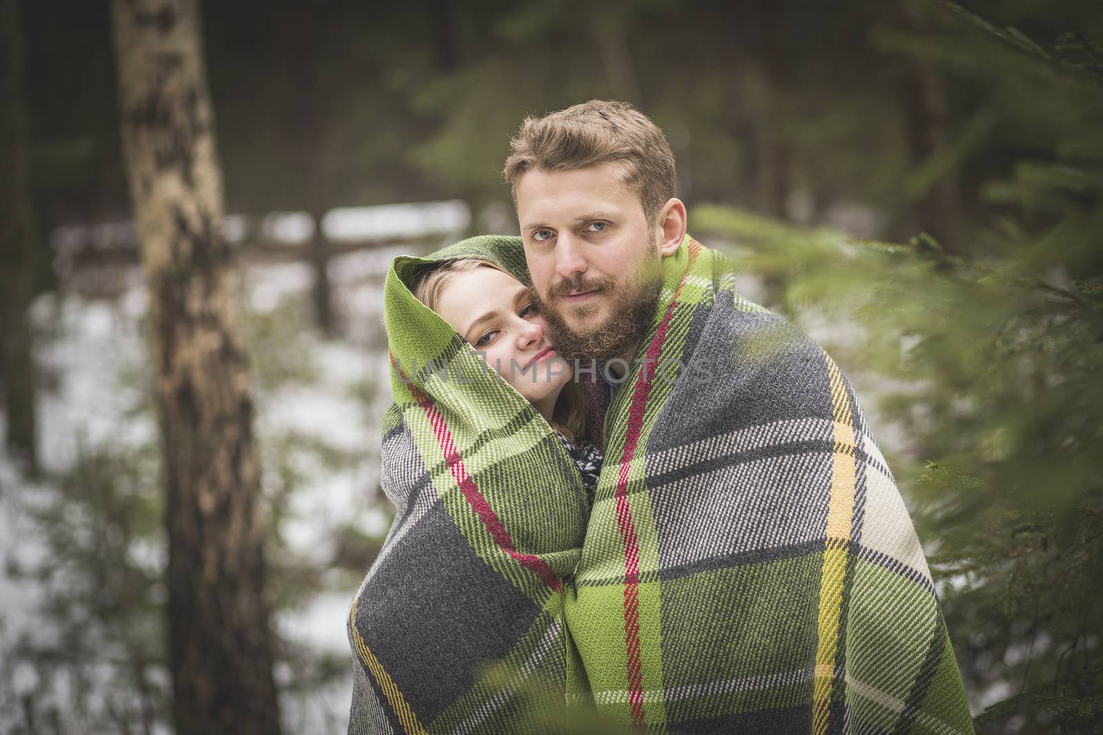 Young couple winter forest walk in a warm blanket  by Kor