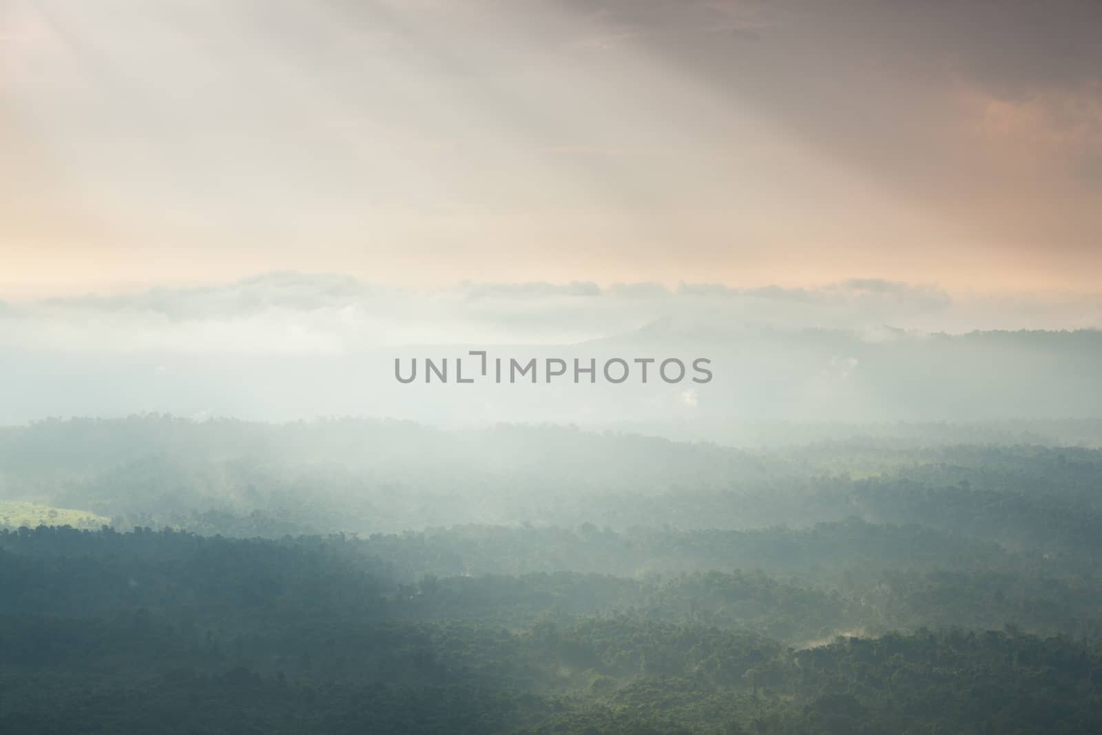 Sunlight shines through the clouds into the mountains and forests. Mist-covered mountains and trees.