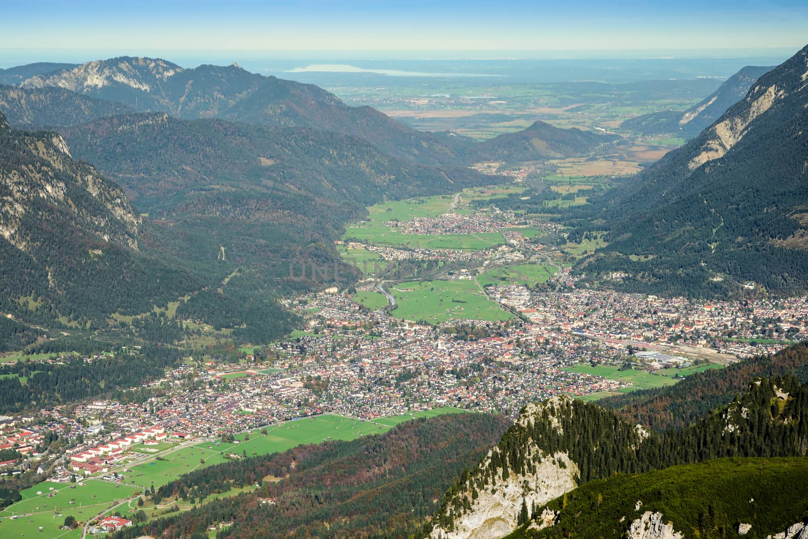 Aerial view of green valley with small town on rim of Alps mountains