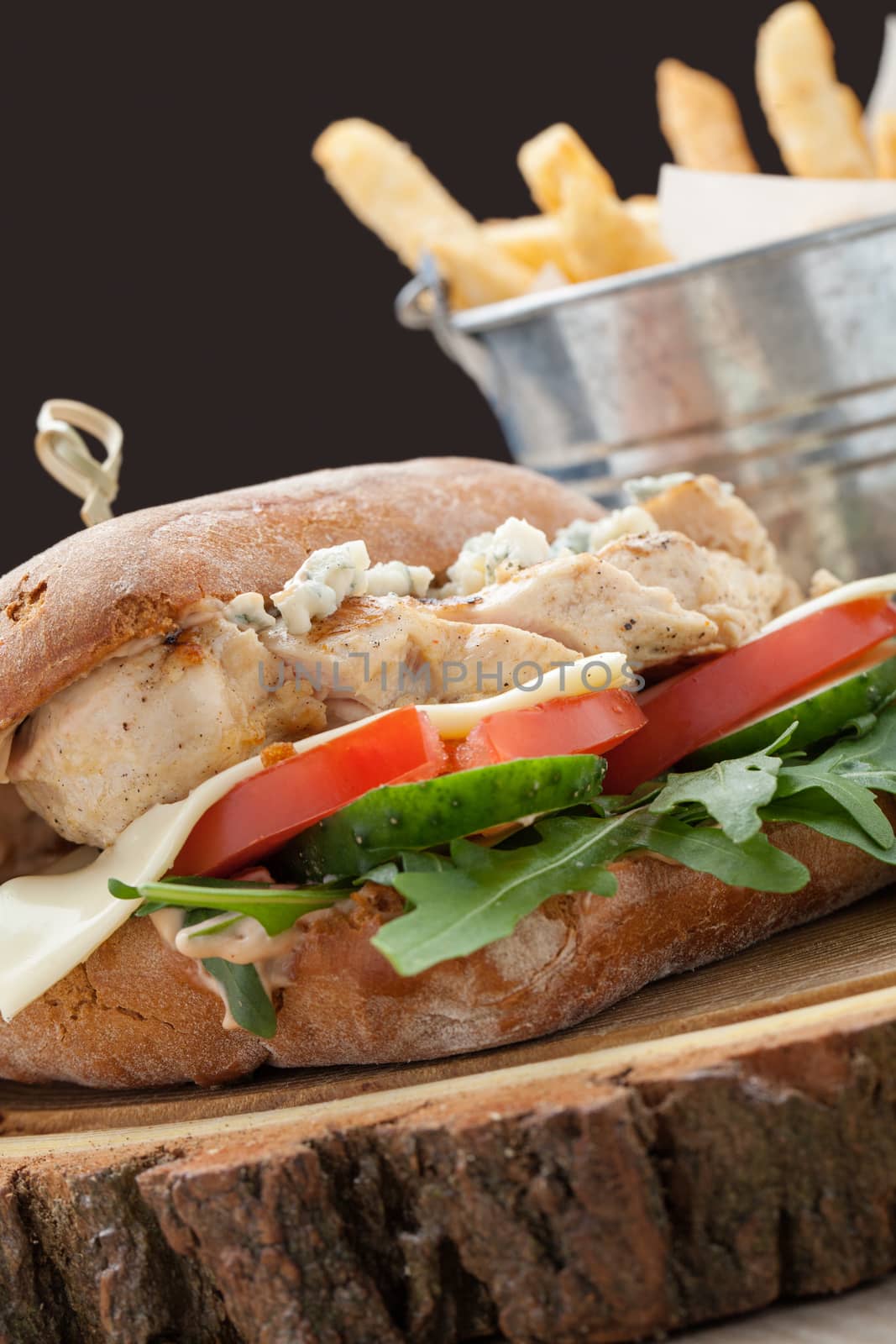 Healthy wheat sandwich burger with BBQ  grilled chicken steak, cheese, tomato, rocket salad, cucumber, fried potato and mustard sauce  served for eating on wooden board