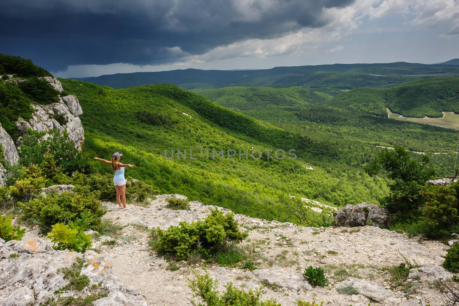 Young woman enjoying the storm at the edge of the cliff, Crimea, Ukraine