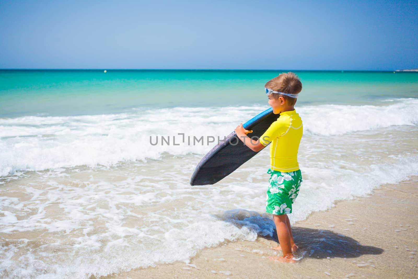 Little boy in yellow has fun surfing