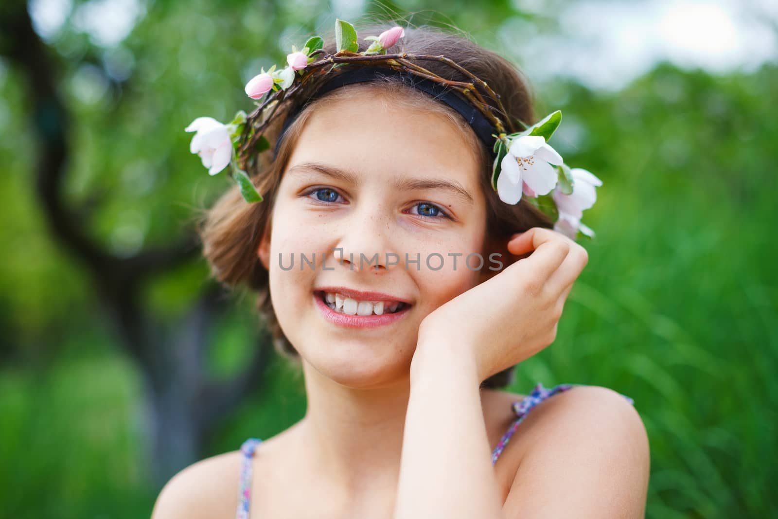 Portrait of adorable girl in blooming apple tree garden on spring day