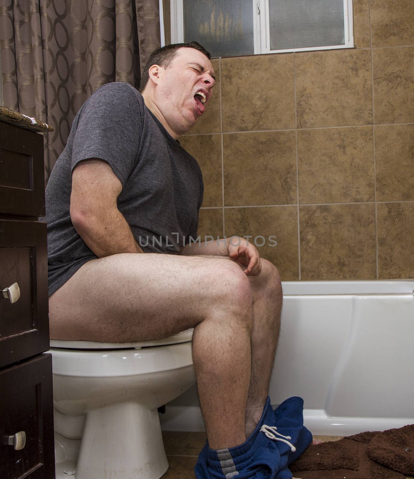 Male on a toilet in the bathroom making a funny face from masterbating