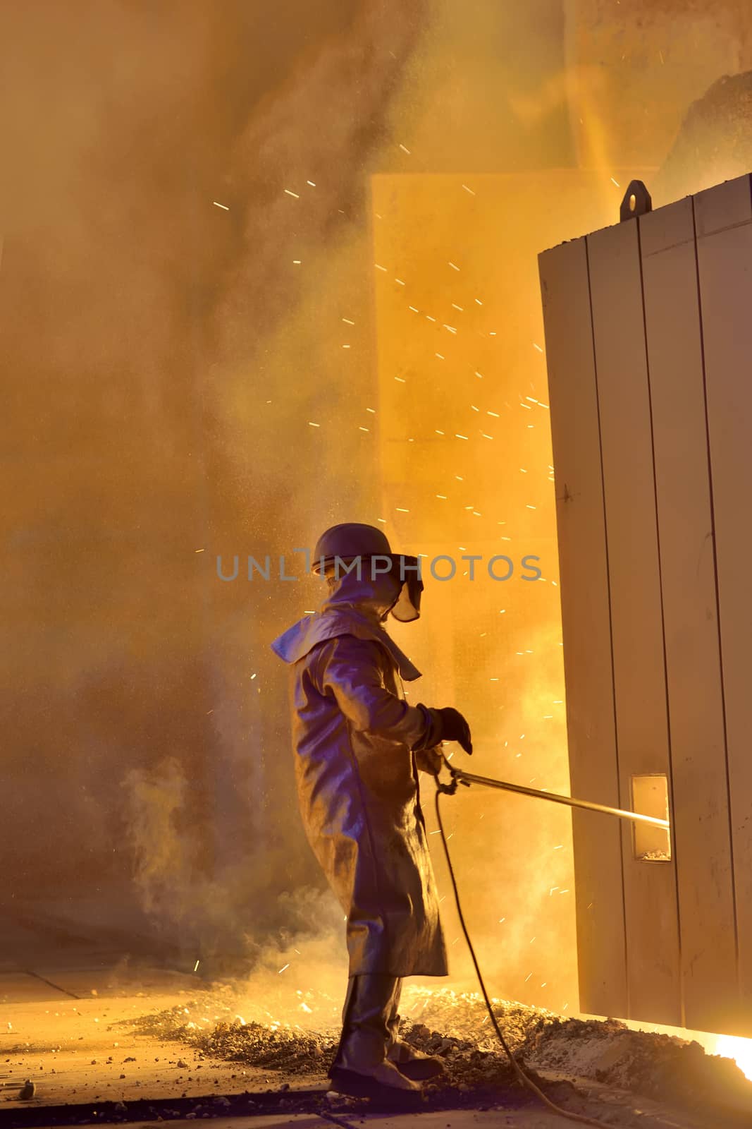 A steel worker takes a sample from oven