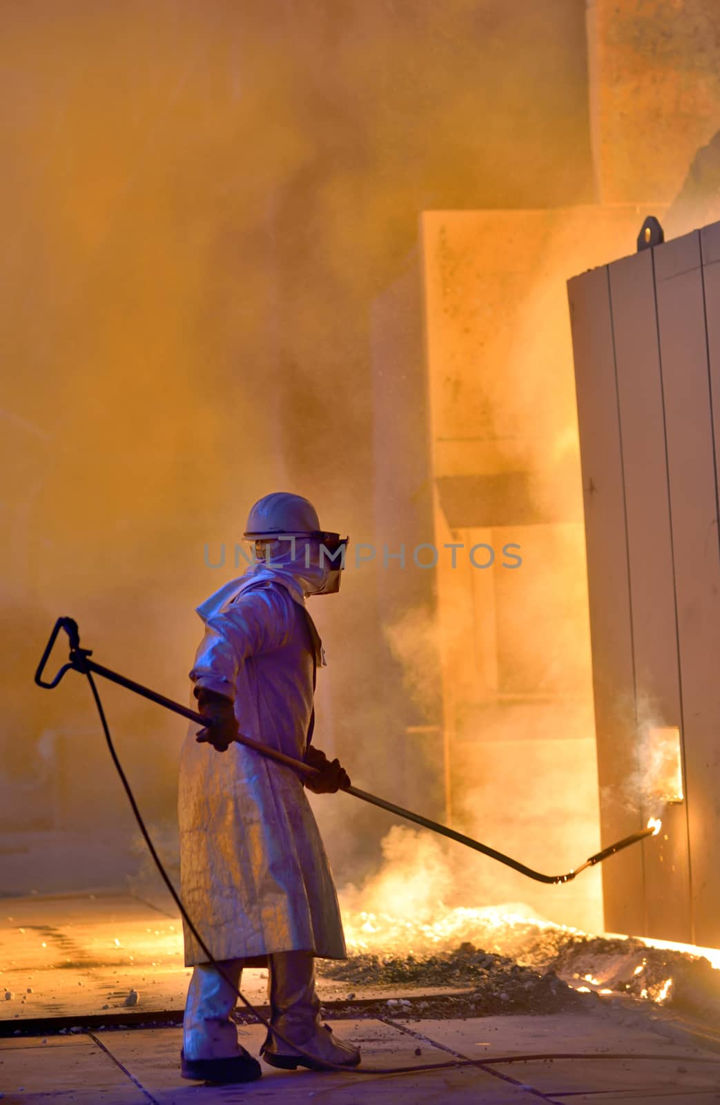 A steel worker takes a sample of hot steel