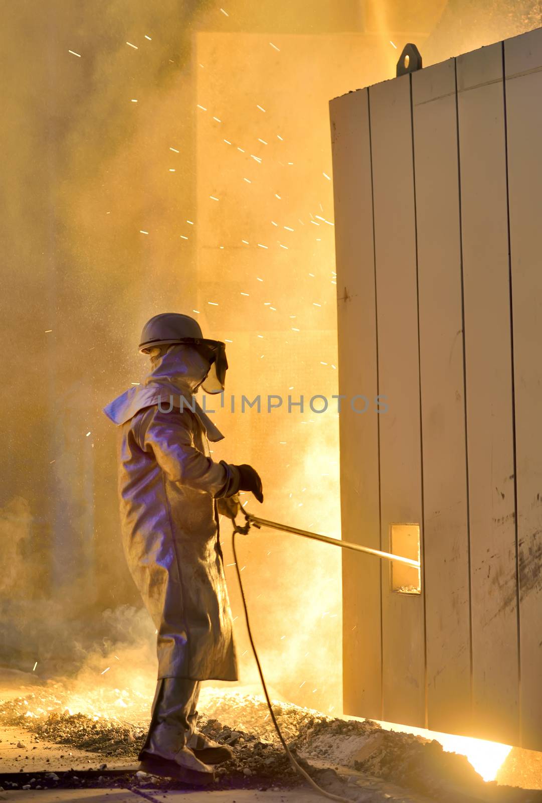 A steel worker takes a sample from oven