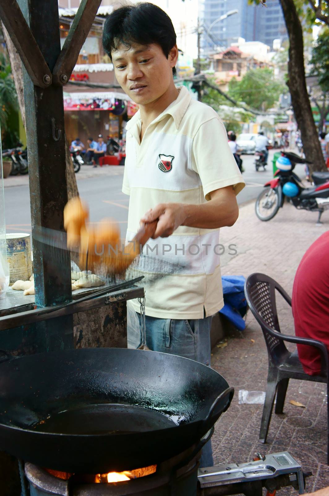 HO CHI MINH CITY, VIET NAM- DEC 17: Vietnamese food at Sai gon street, fried dumplings is popular street food, fast food, family of vendor make dish on pavement, Saigon, Vietnam, Dec 17, 2014