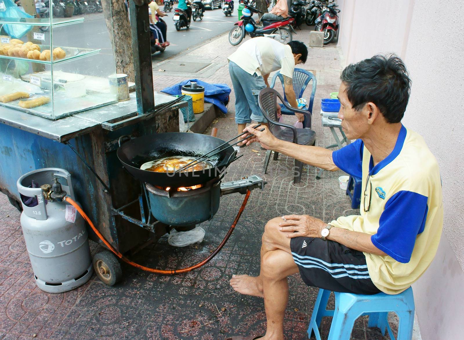 HO CHI MINH CITY, VIET NAM- DEC 17: Vietnamese food at Sai gon street, fried dumplings is popular street food, fast food, family of vendor make dish on pavement, Saigon, Vietnam, Dec 17, 2014