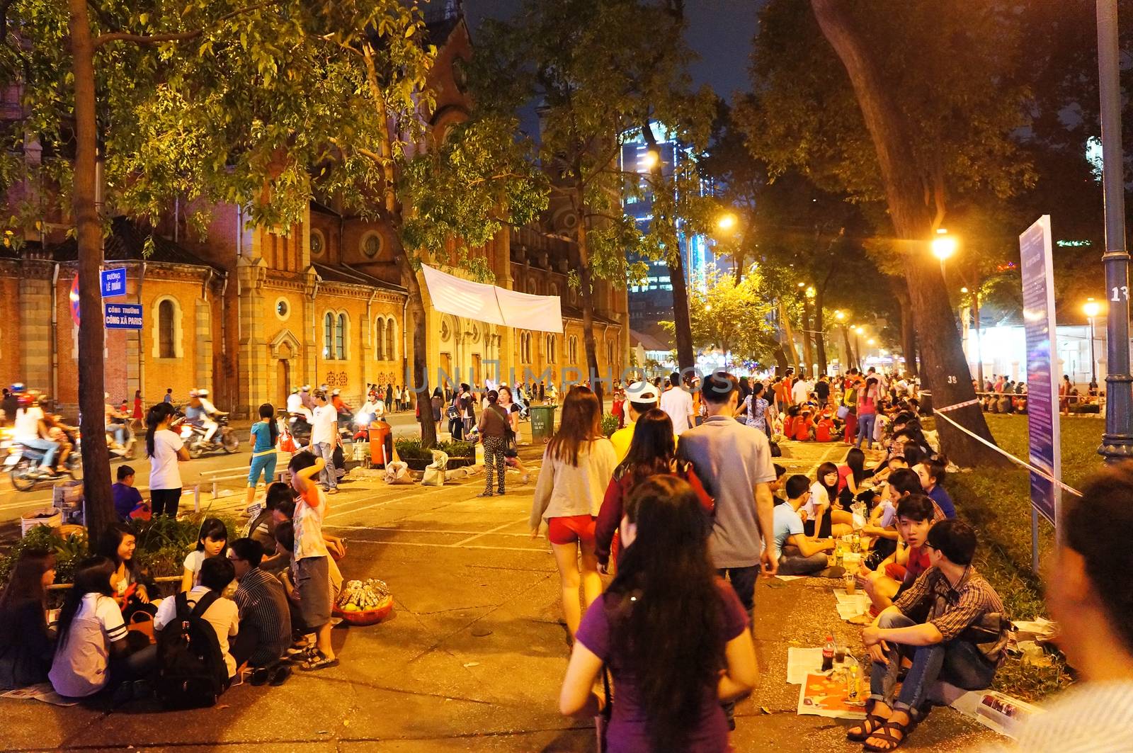 HO CHI MINH CITY, VIET NAM- DEC 24: Crowded atmosphere at Duc Ba Cathedral at Xmas night, under yellow lamp, young people sit on pavement, enjoy bet cafe, is youth lifestyle, Vietnam, Dec 24, 2014