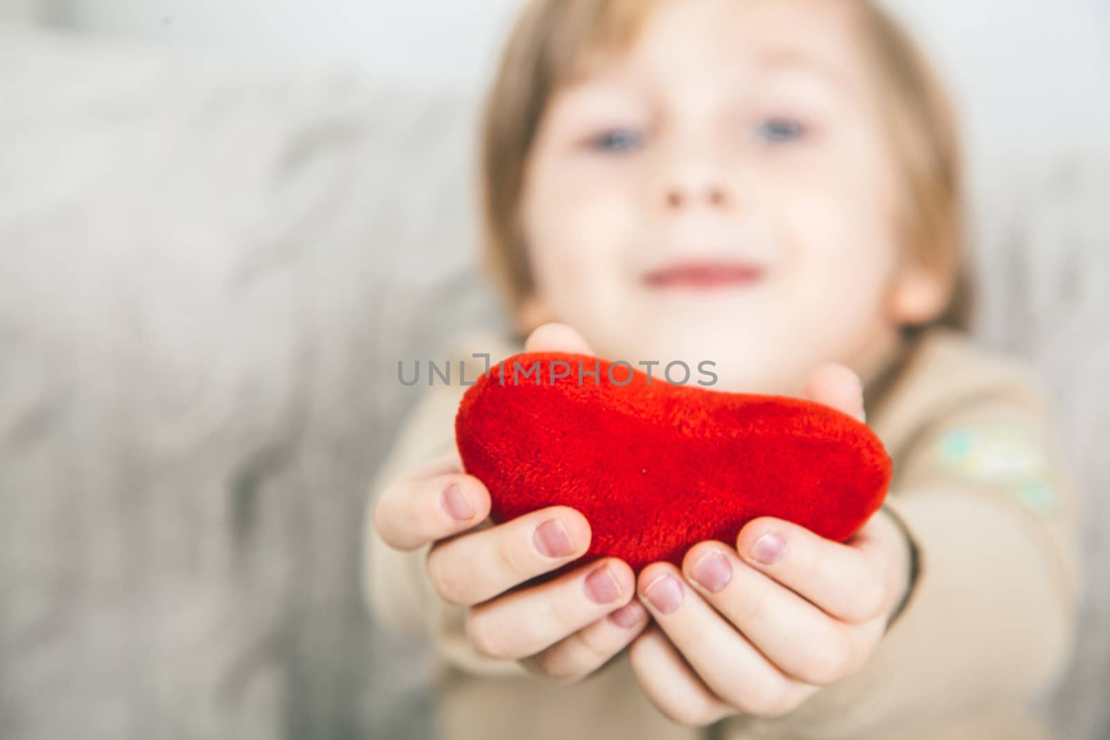 Cute young boy with a red heart in his hands
