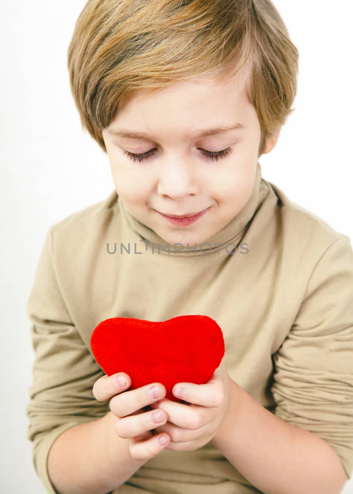 Cute young boy with a red heart in his hands