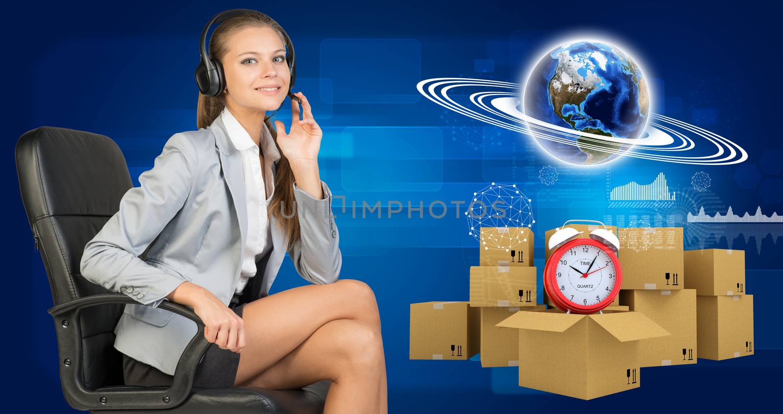 Businesswoman in headset, sitting on office chair, her hand on microphone, sitting, looking at camera, smiling. Beside are commodity boxes with alarm-clock on top of one. Globe with horisontal rings, graphs and other virtual elements as backdrop. Element of this image furnished by NASA
