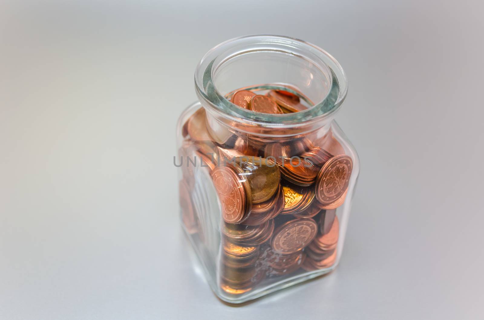 Detached glass filled with various Euro cent coins.