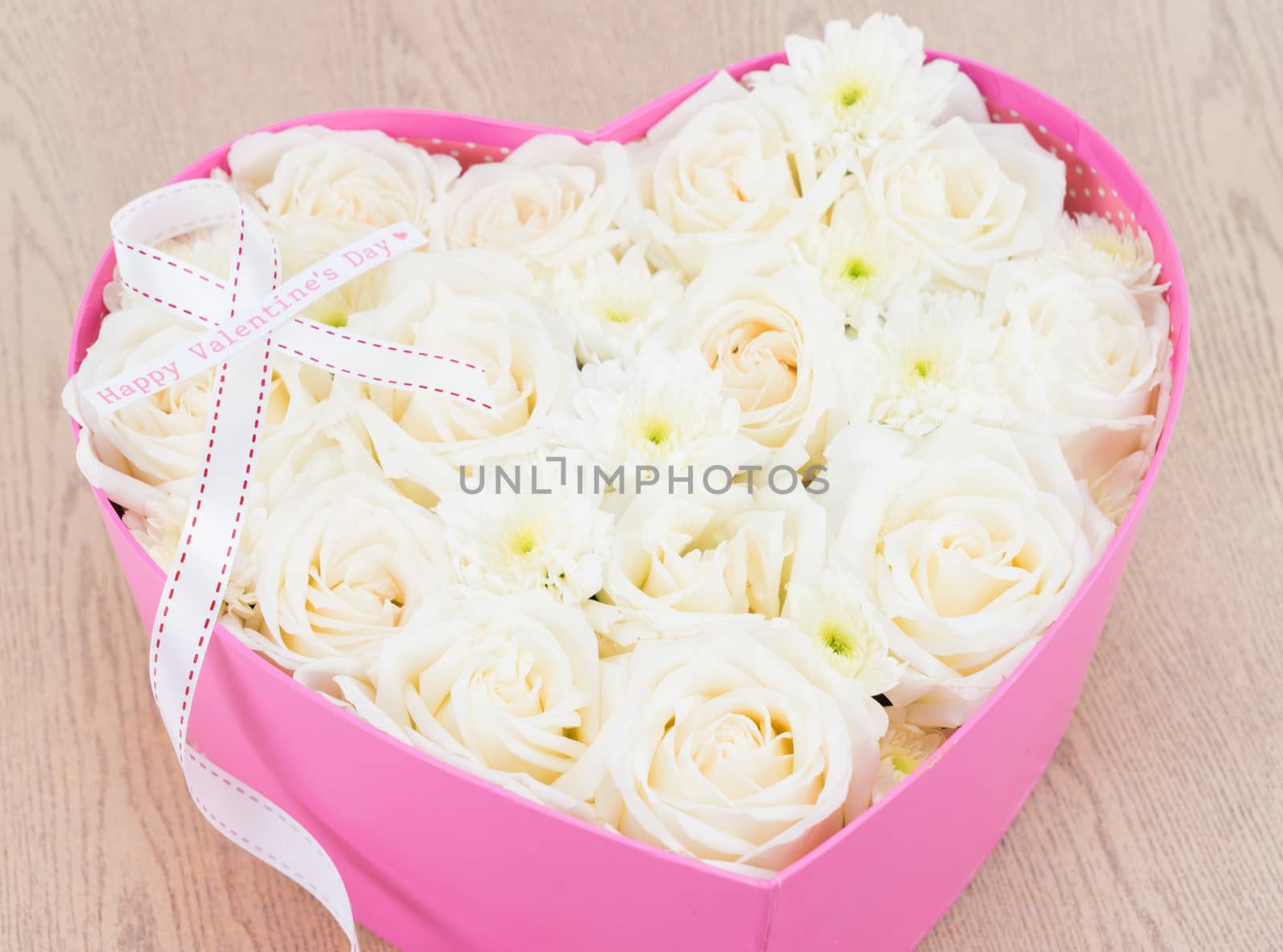 White roses and pearl and diamond held in the heart shape box with "happy valentine's day" text label. gift for valentine 's day on wooden background