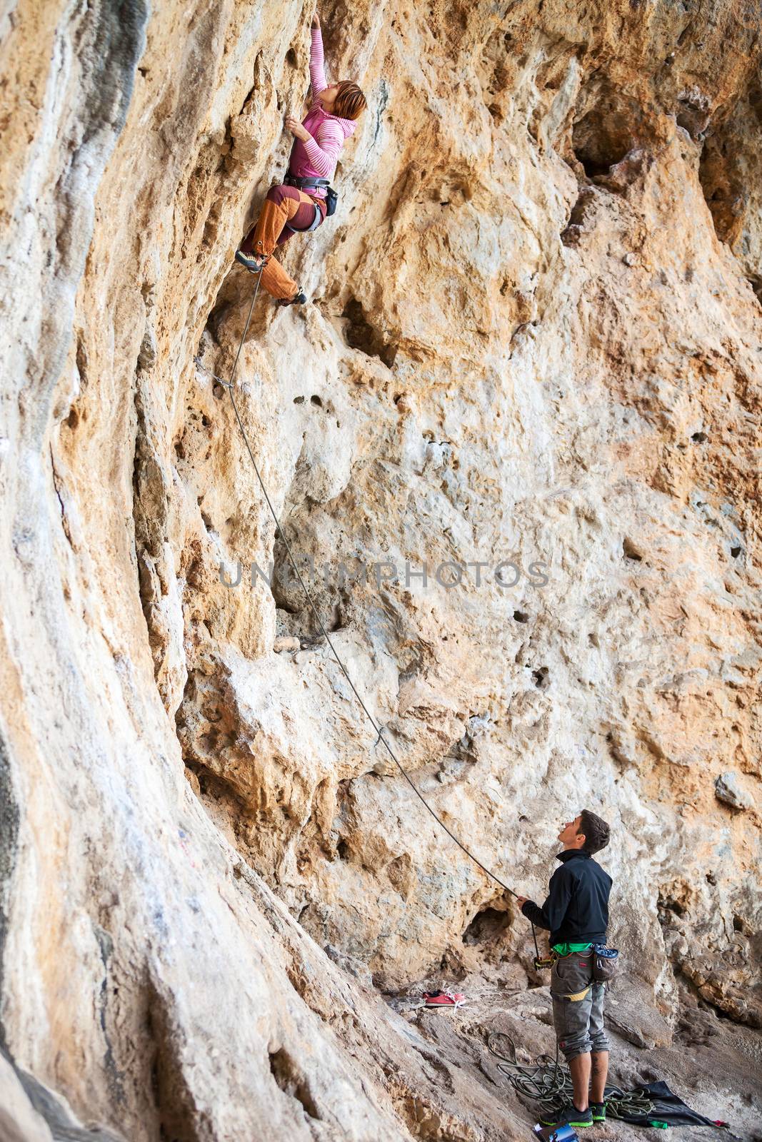 Young woman lead climbing on natural cliff by photobac