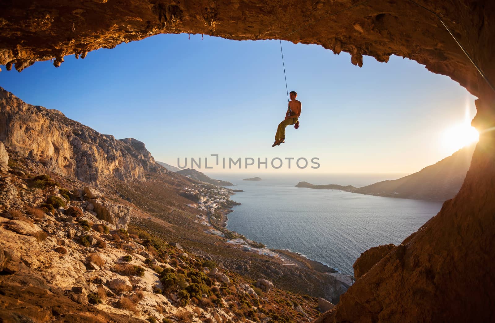 Rock climber hanging on rope while lead climbing by photobac
