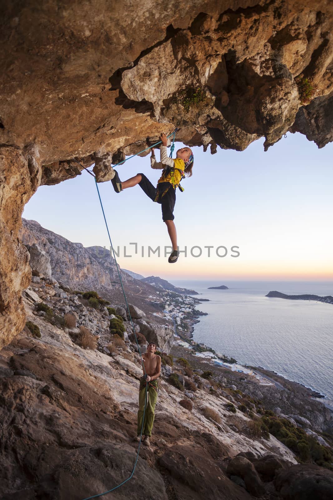 Seven-year old girl climbing a challenging route, father belaying