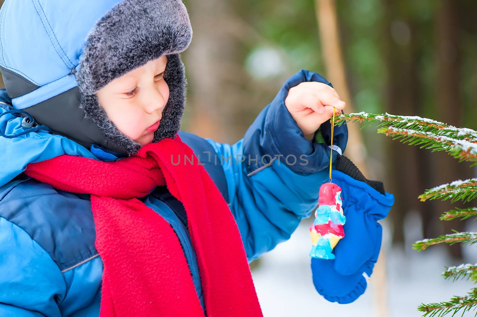 boy hangs on the Christmas tree decoration in the forest by kosmsos111