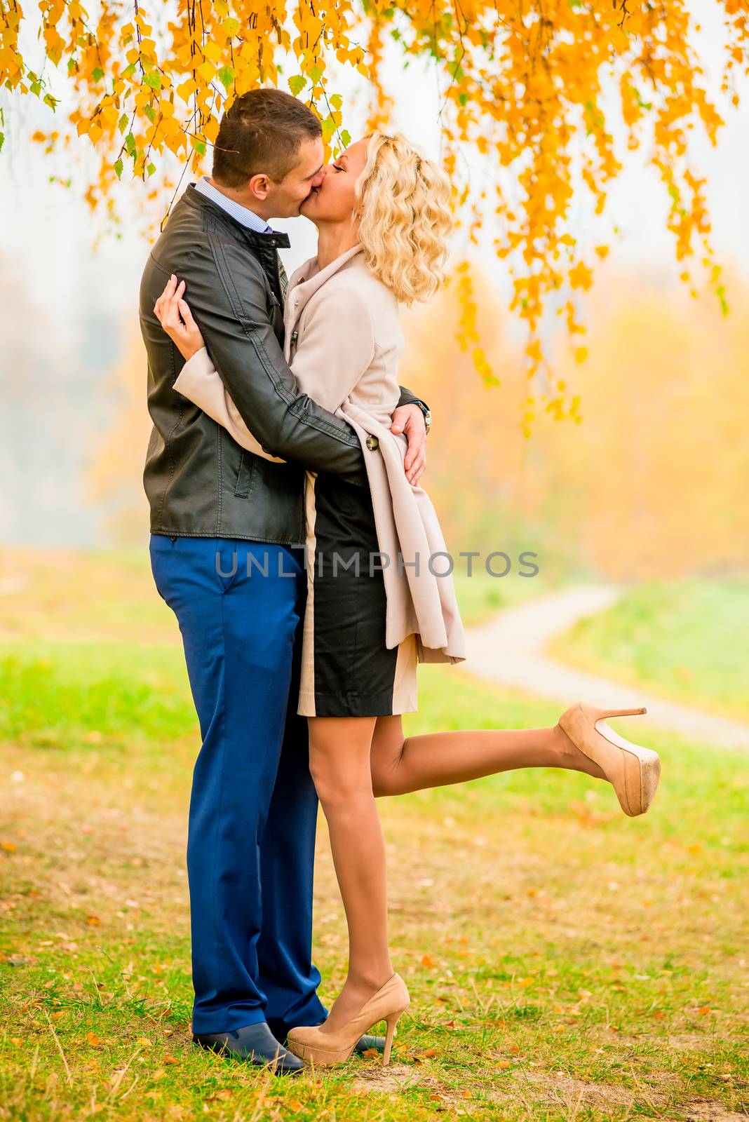 a loving couple kissing in autumn park