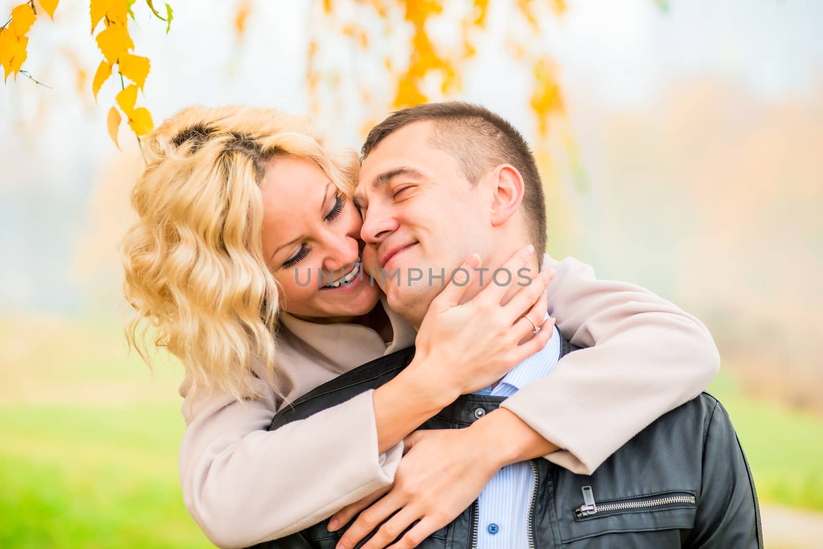 blonde embraces her lover outdoors in autumn park