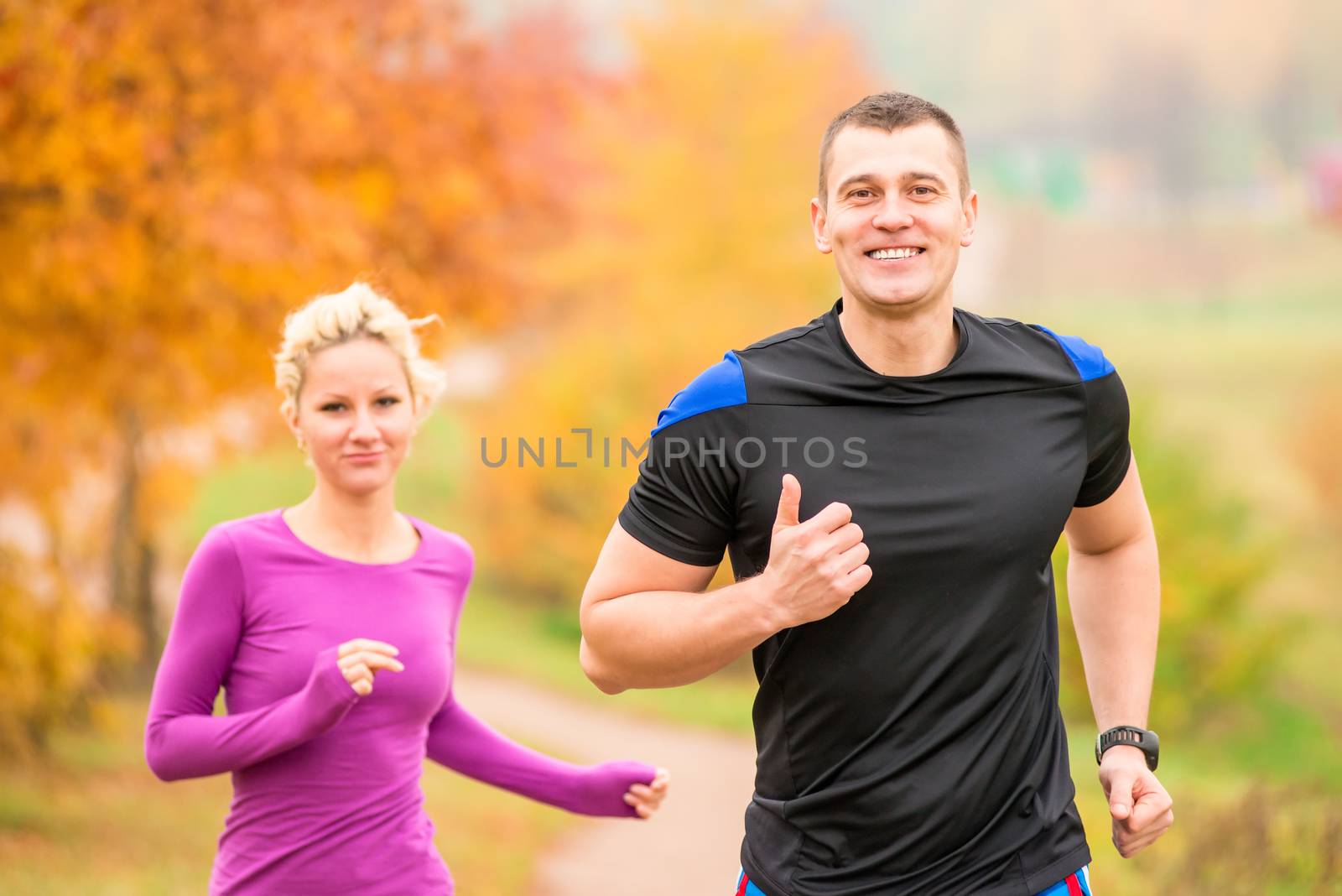 cheerful young athletes jogging autumn morning