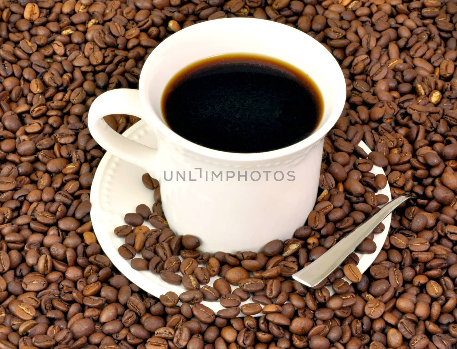 Coffee cup and saucer surrounded by dark beans