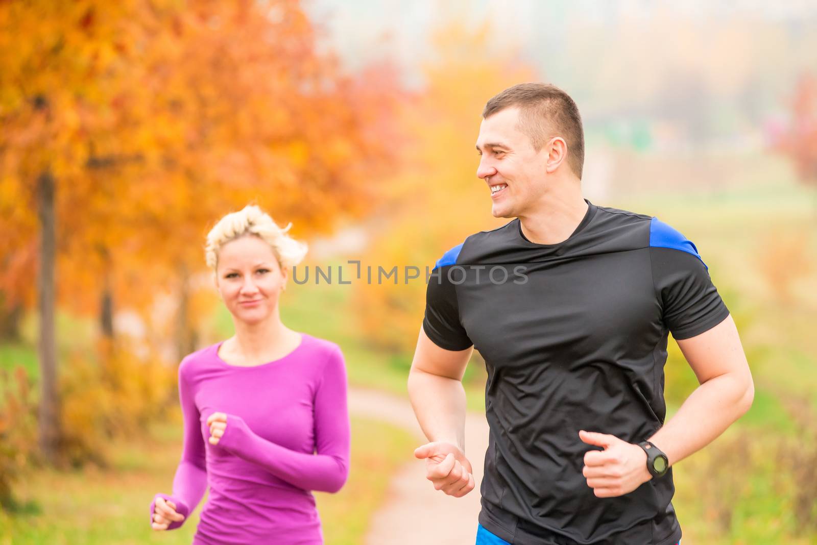 healthy lifestyle - jogging. a man and a woman running in the morning in the park