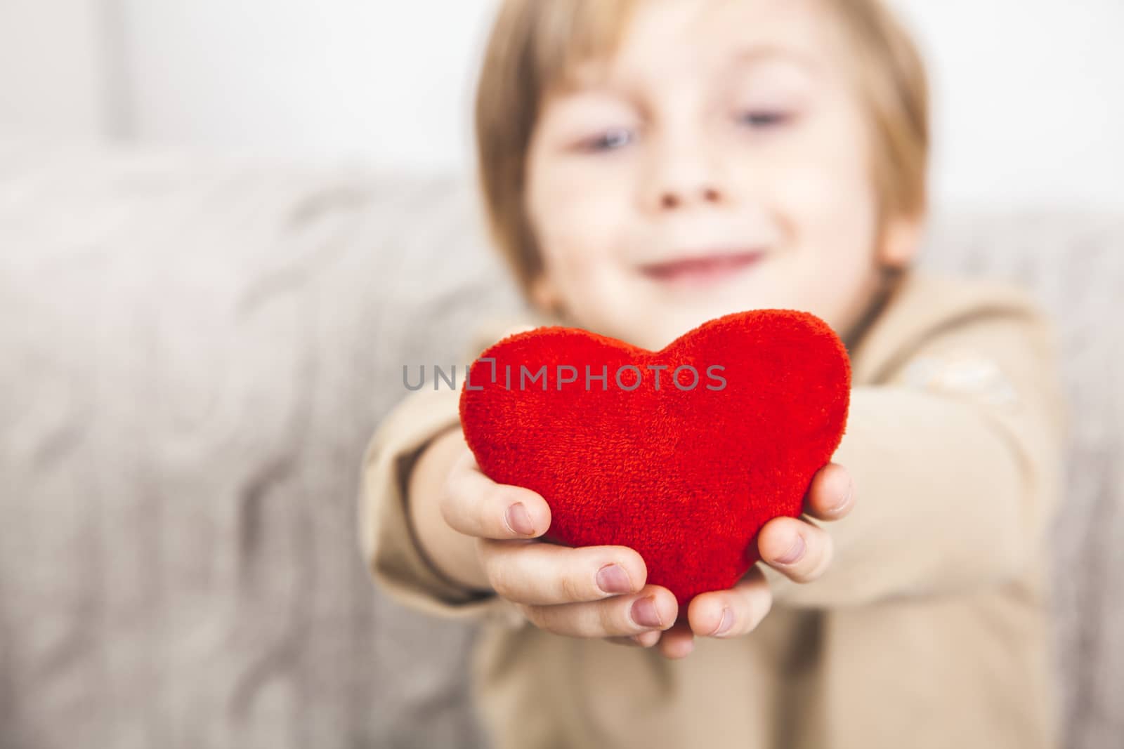 Cute young boy with a red heart in his hands