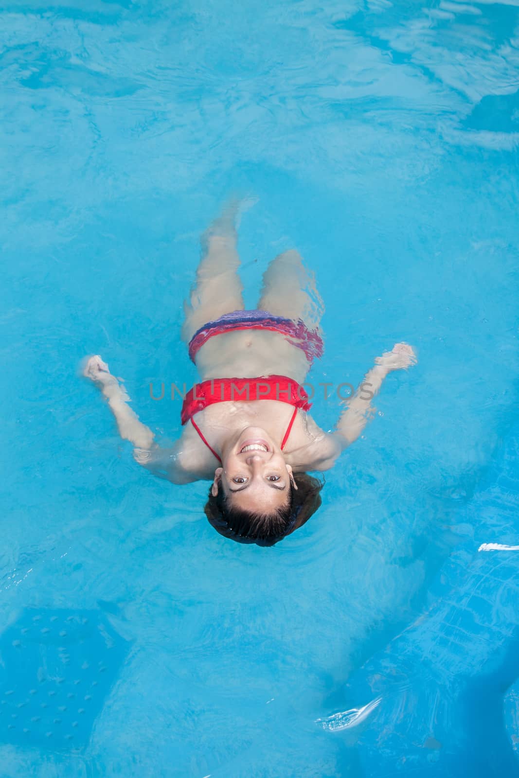 Woman floating in the pool by ifilms
