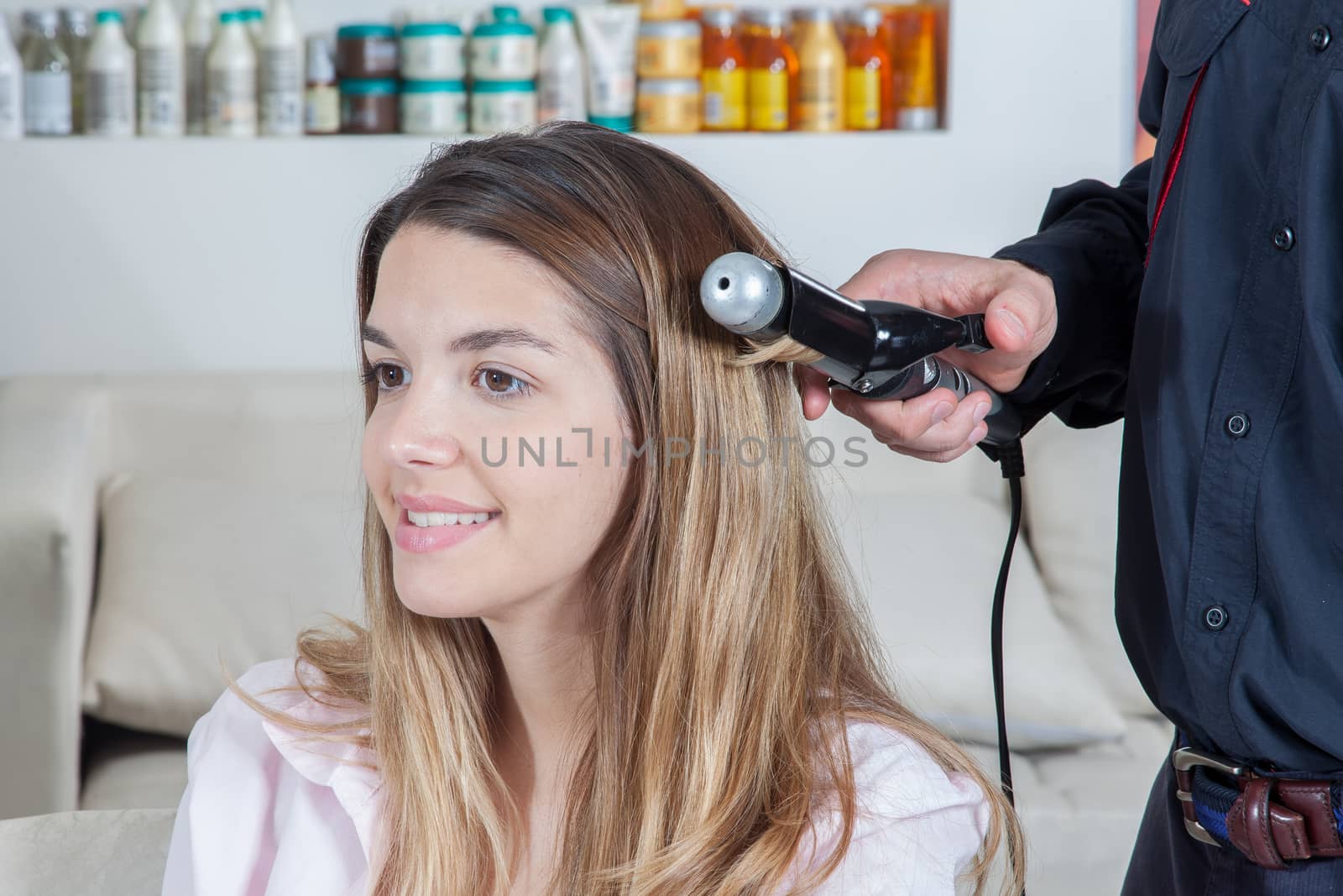 The coiffeur use a curling iron