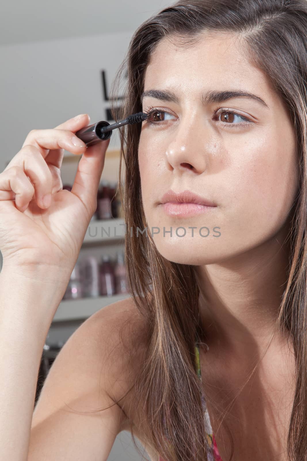 Concentrated woman applying mascara by ifilms