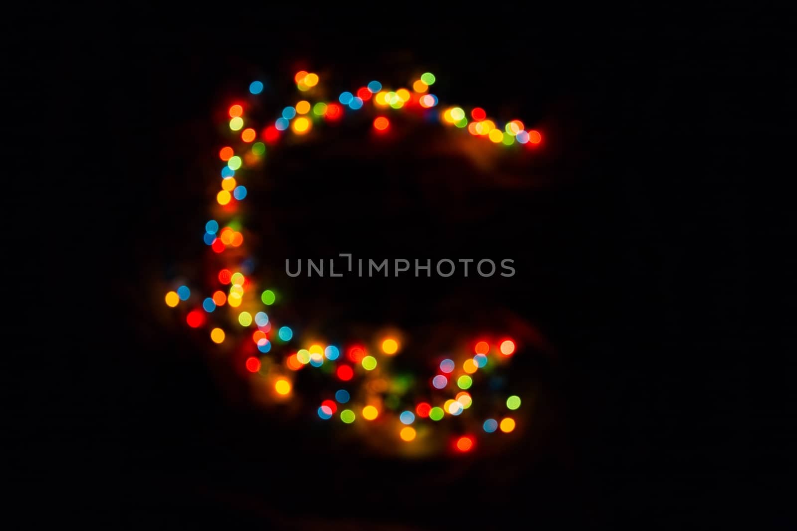 colorful letter C made of blurred circular bokeh on black background