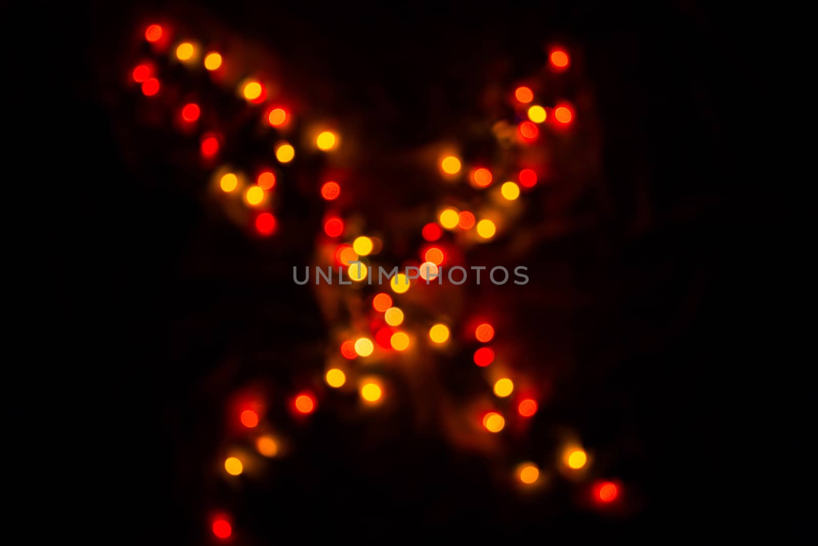 defocused colorful letter X made of blurred circular bokeh on black background