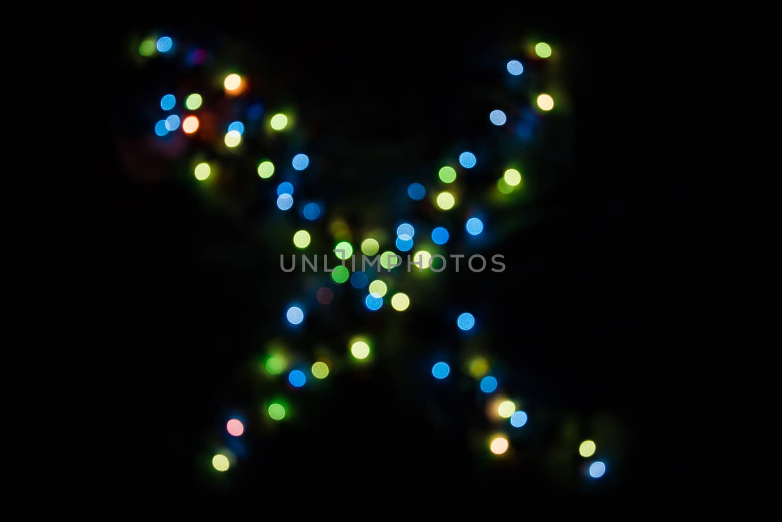 defocused colorful letter X made of blurred circular bokeh on black background