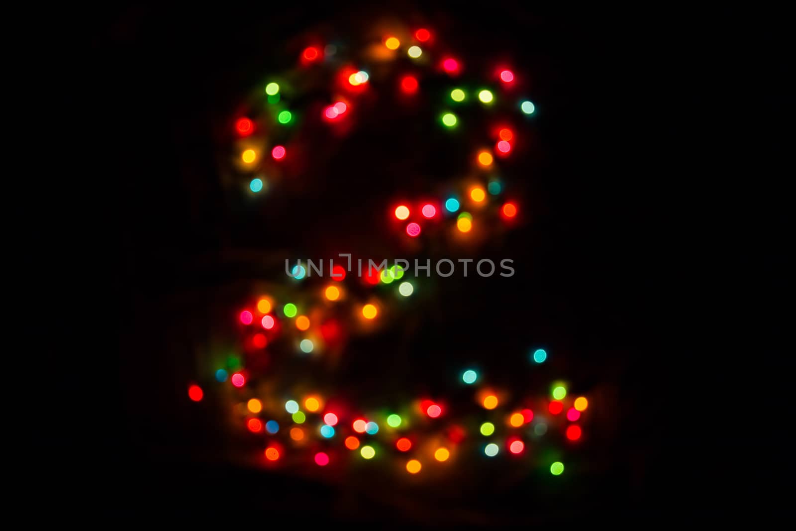 defocused colorful number two made of blurred circular bokeh on black background