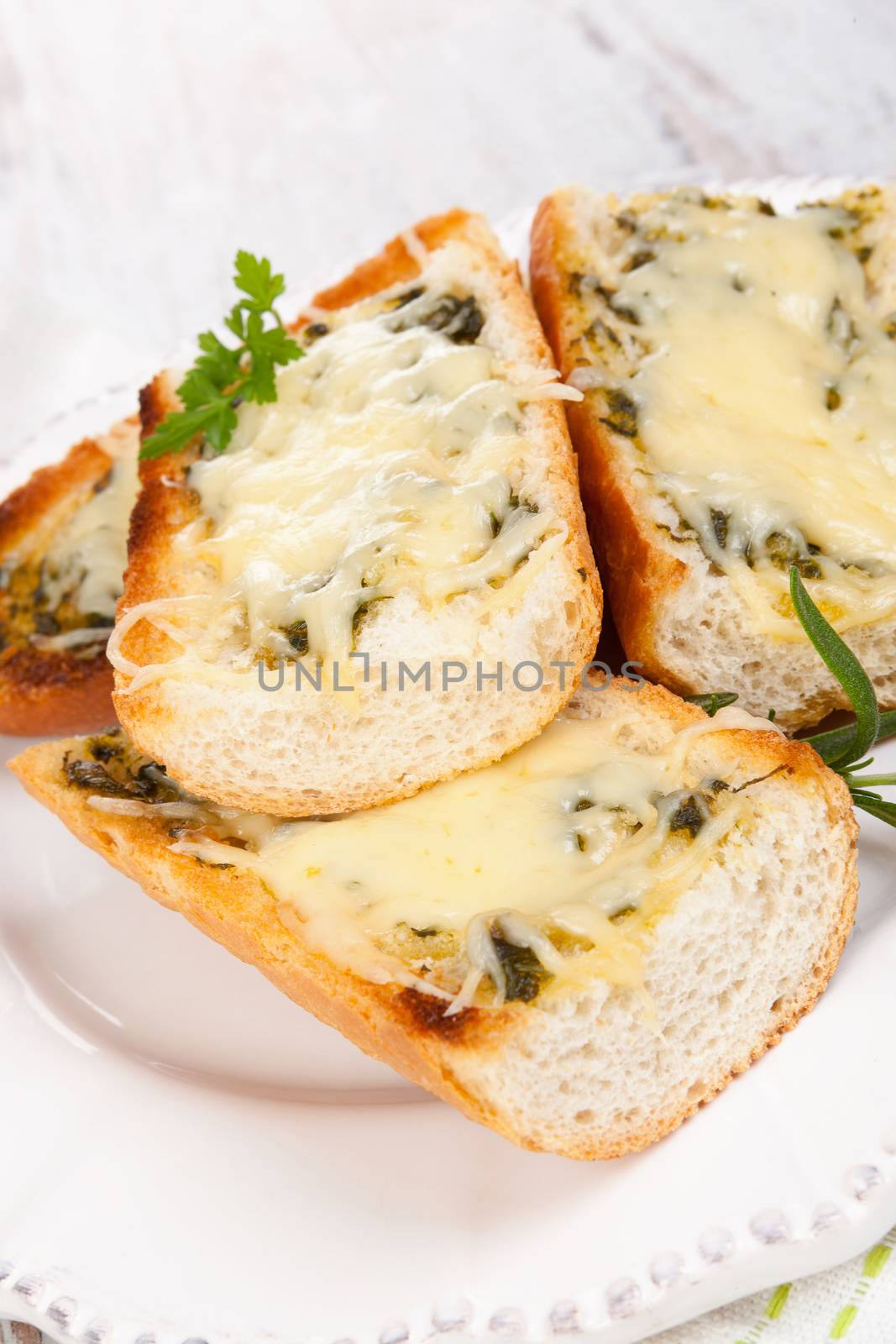 Garlic baguette with melted cheese on white wooden background. Culinary eating. 
