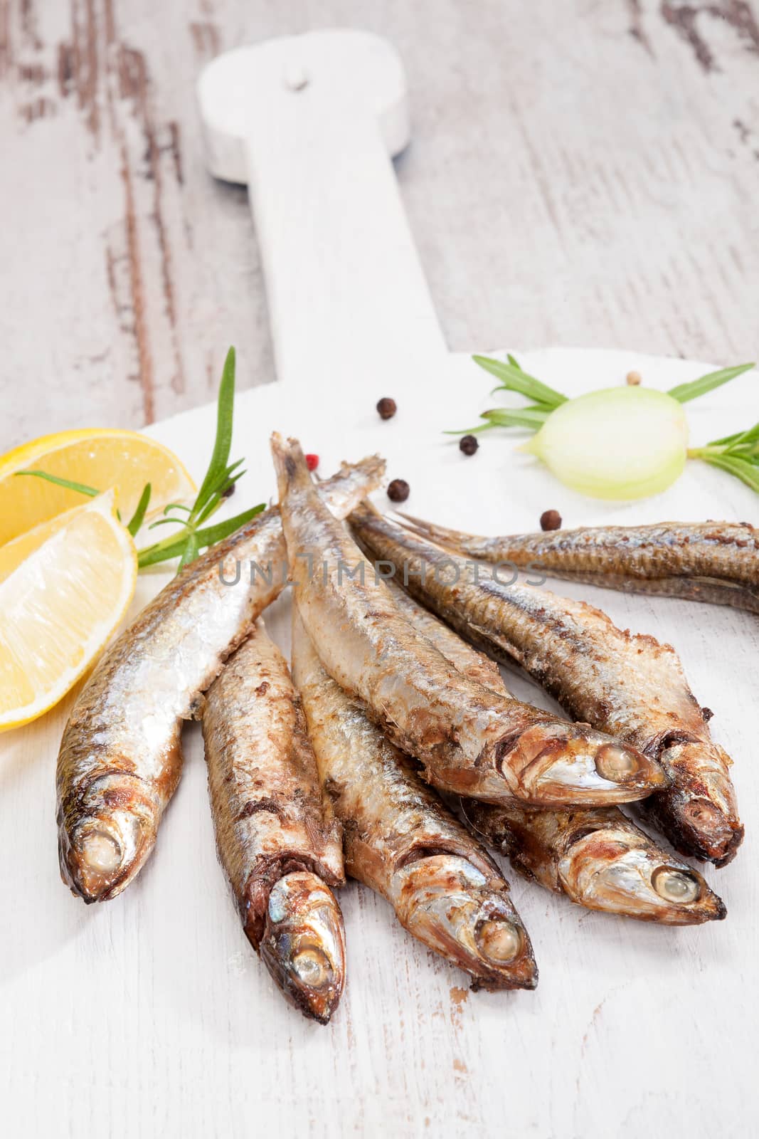 Culinary seafood eating. Grilled sardines on wooden background with fresh herbs and lemon. Culinary mediterranean eating. 