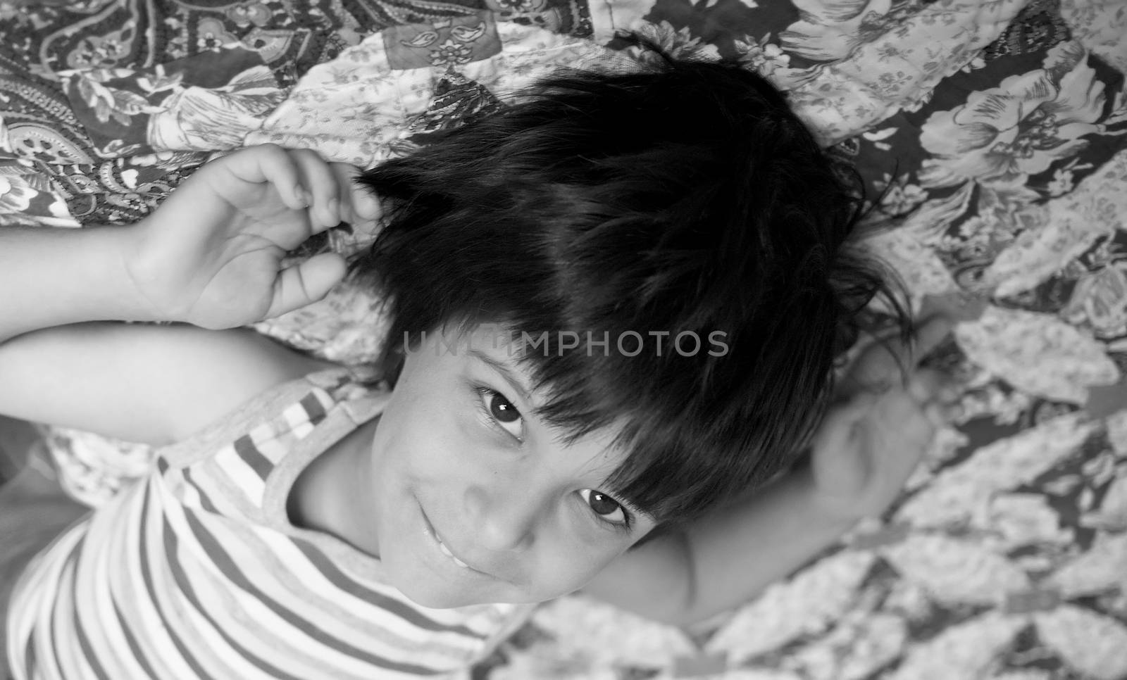 Smiling boy lying, arms outstretched, soft focus