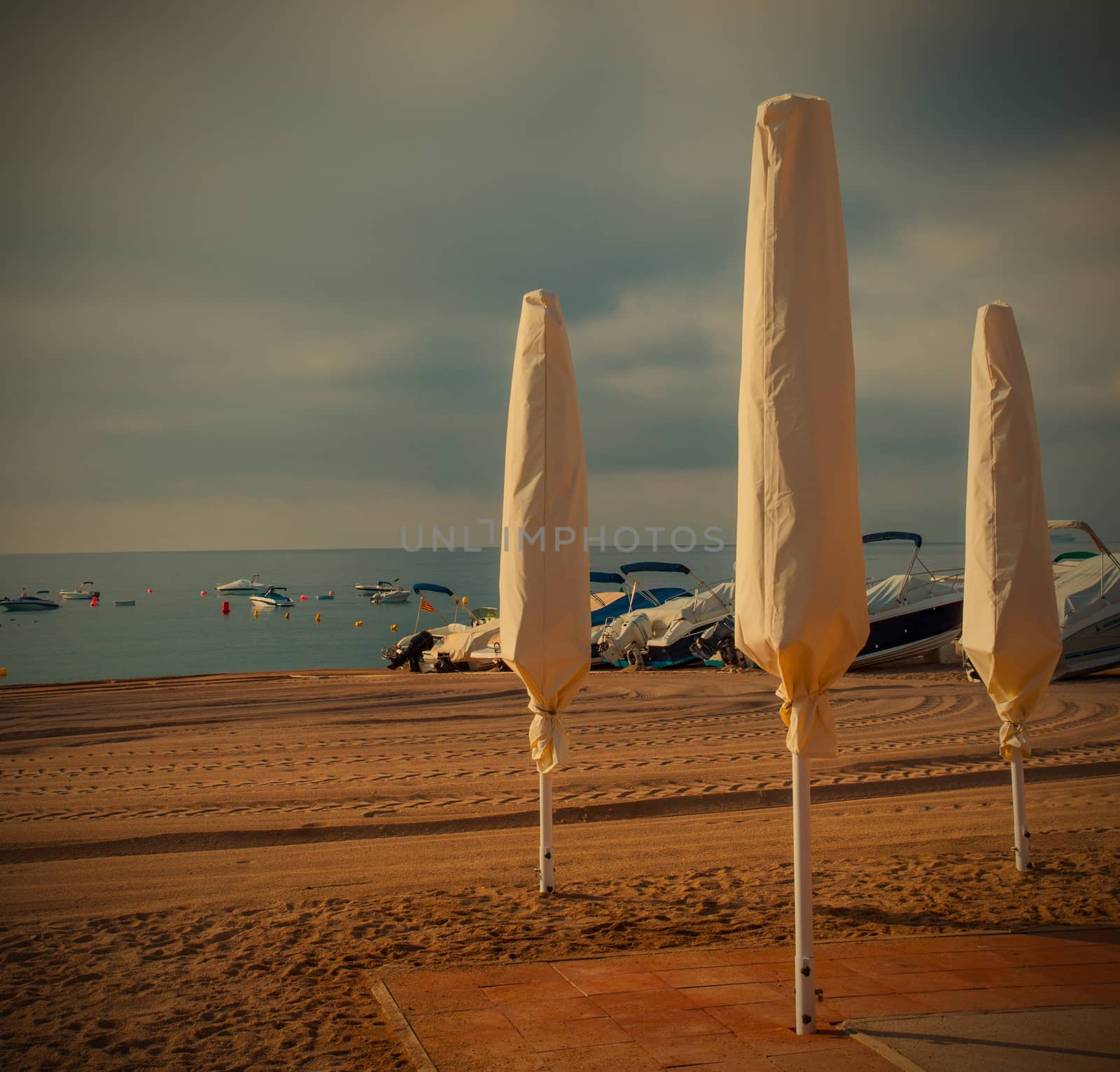 beach, folded umbrellas, early morning by Astroid