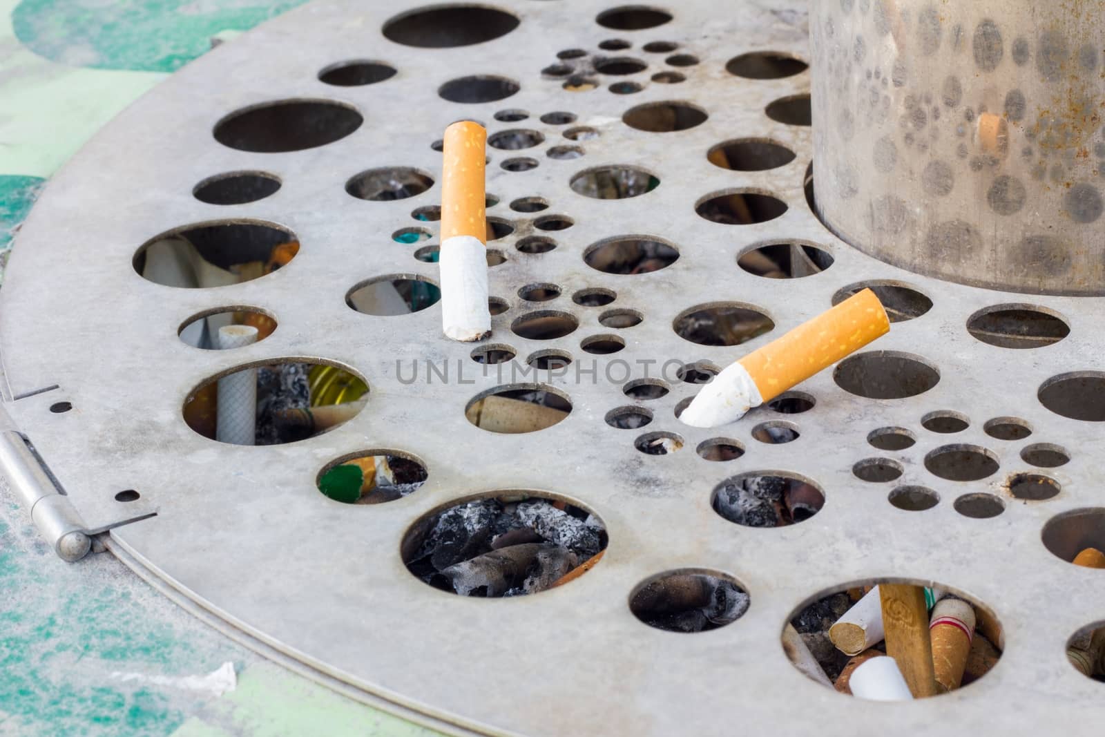 two cigarettes on a steel old public ash-tray