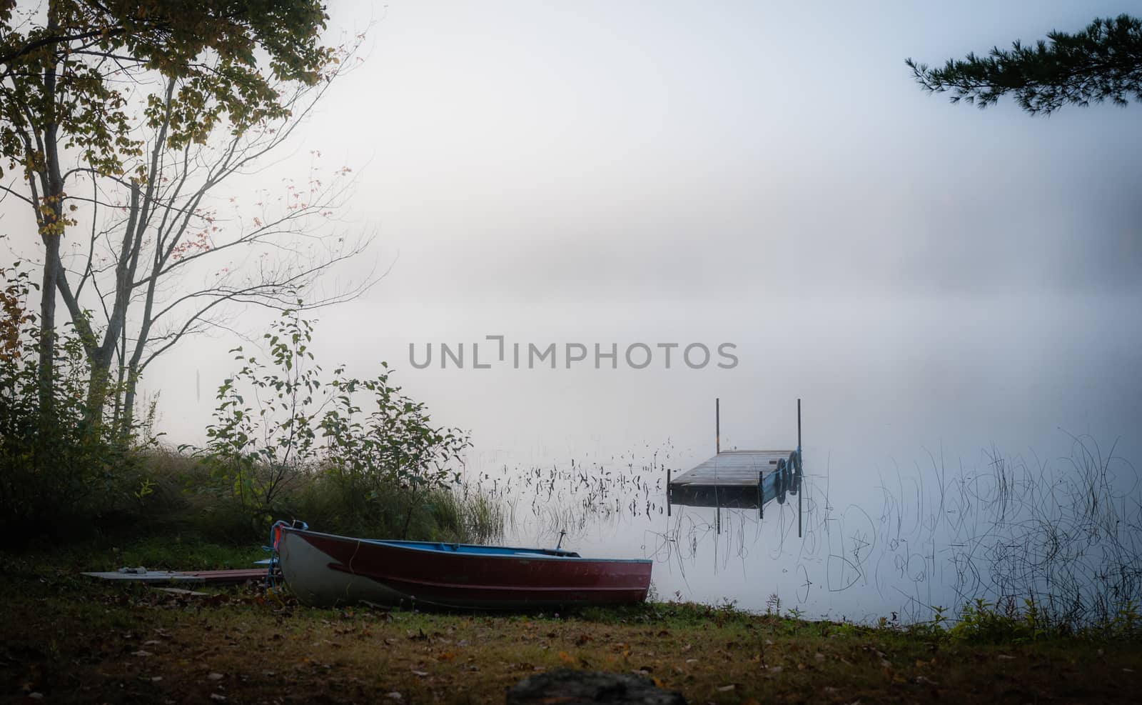 Early morning sunrise reveals what September night cool air does when it meets warmer lake water.  emply dock and boat await the day.