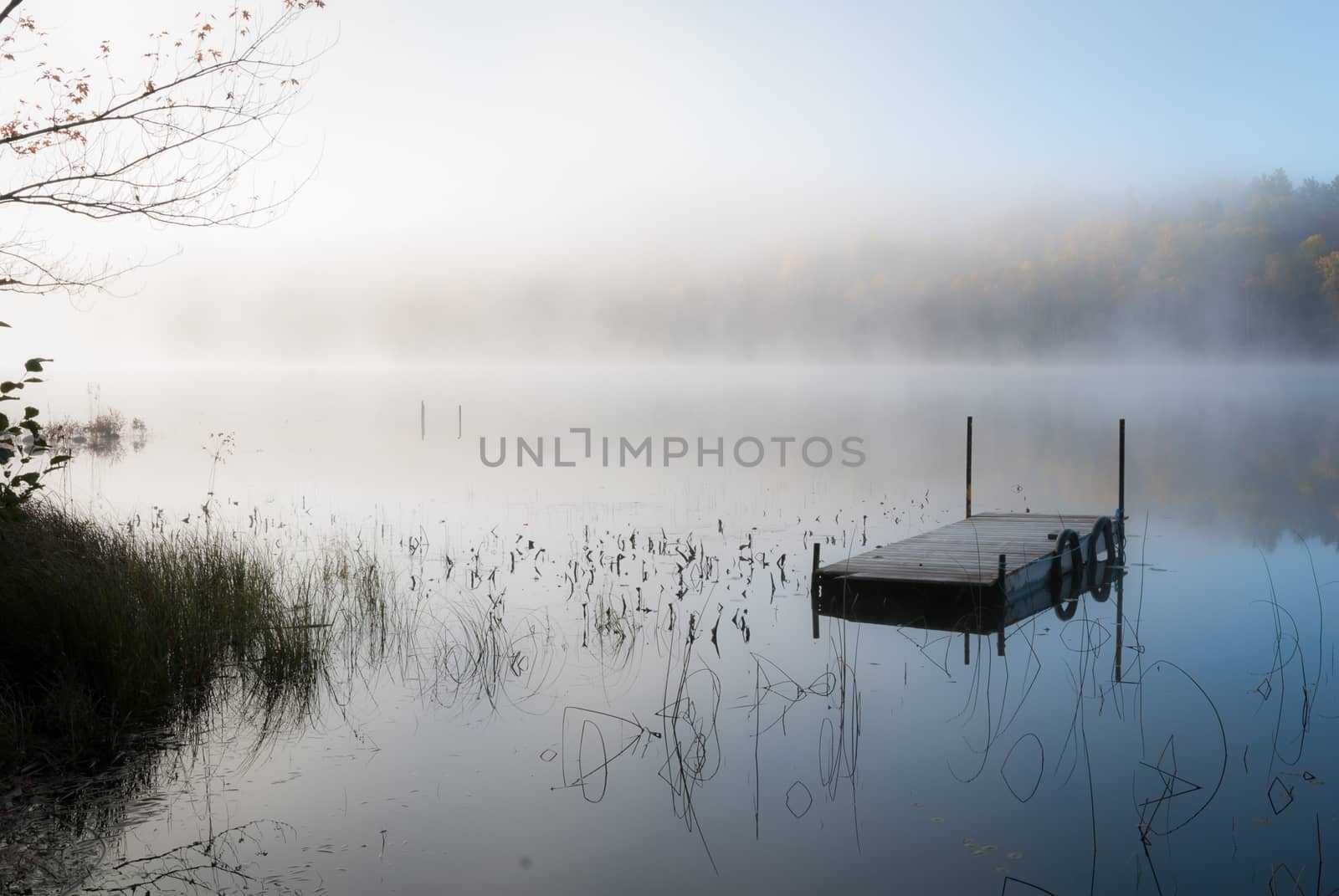 Early morning sunrise slowly burns off accumulated overnight fog over a Northern Ontario lake.