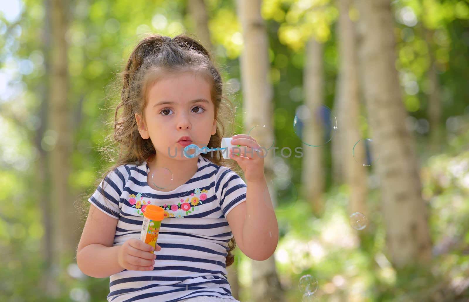Portrait of  lovely little girl blowing soap bubbles