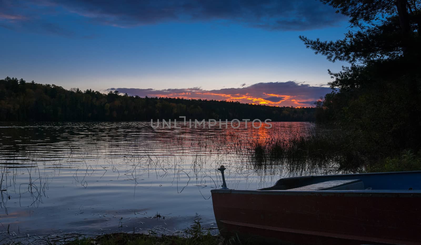 Colourful clouds are reflected on a lake at sundown.