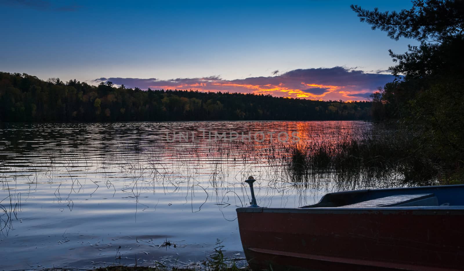 Colourful clouds are reflected on a lake at sundown.