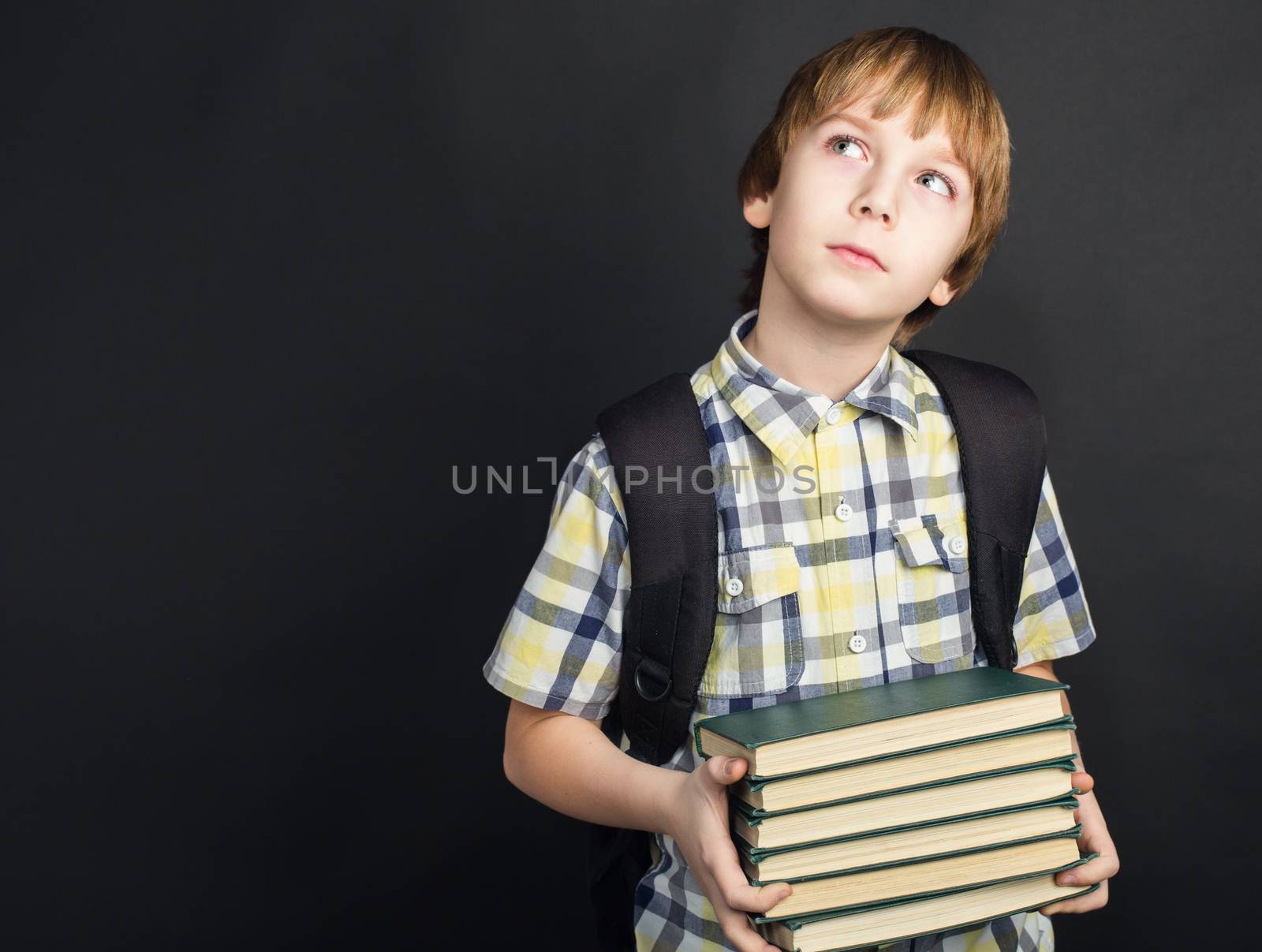 Portrait of diligent student in glasses with heap of books in hands