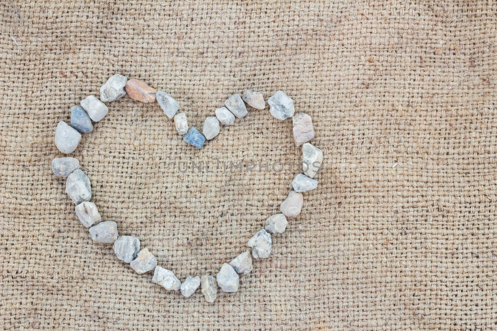 Heart made of stones  on gunnysack, background, with copyspace